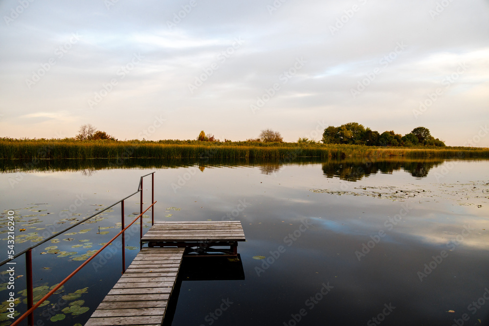 Summer in the countryside - picturesque landscape with a wooden pier in the evening at sunset