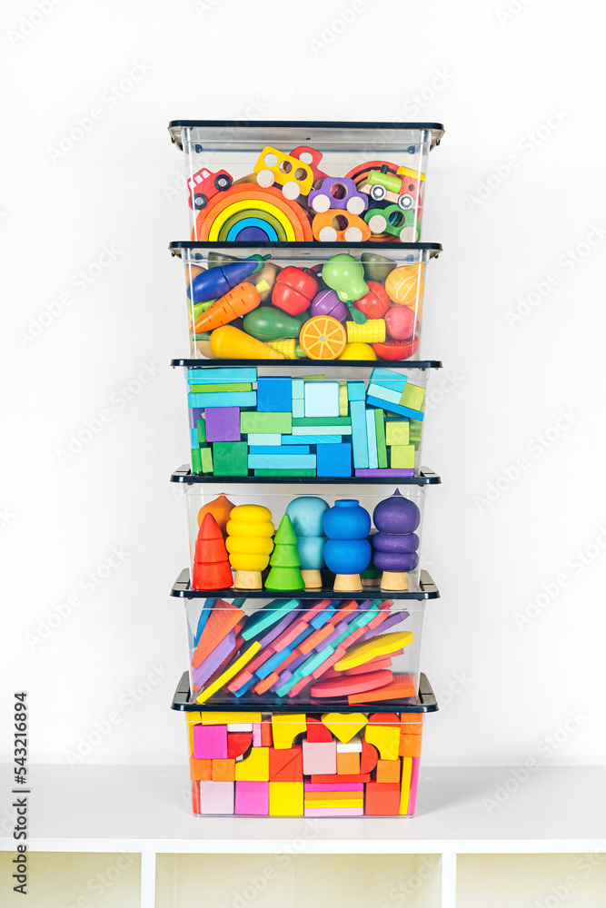 Transparent plastic containers with various children's toys on shelves ...