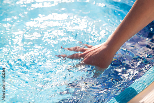 Man's hand in the clear transparent water of the pool,