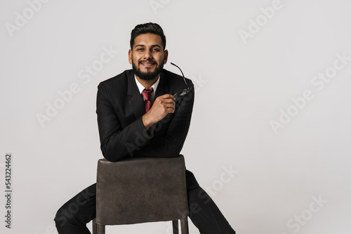 Portrait of indian man in black suit sitting on chair photo