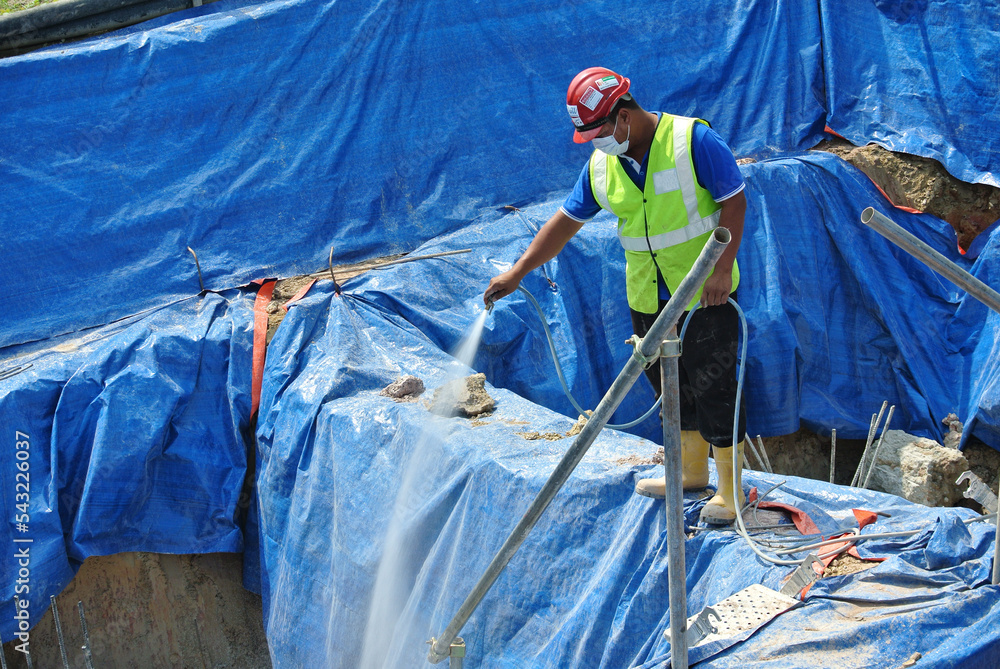 JOHOR, MALAYSIA -JUNE 26, 2015: Construction workers spraying the anti termite chemical treatment to the soil at the construction site. 