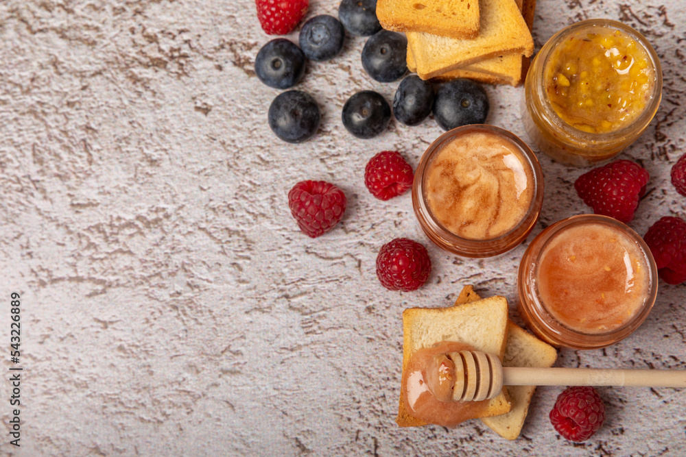Toasted bread toast with jam. A jar of raspberry jam. Delicious toast with sweet jam served for breakfast on the table. Delicious toasts on a textured background. Space for text. Place for copying.