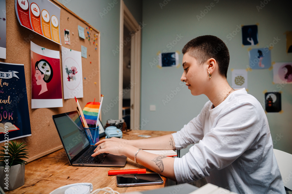 Young white woman working with laptop while sitting at desk