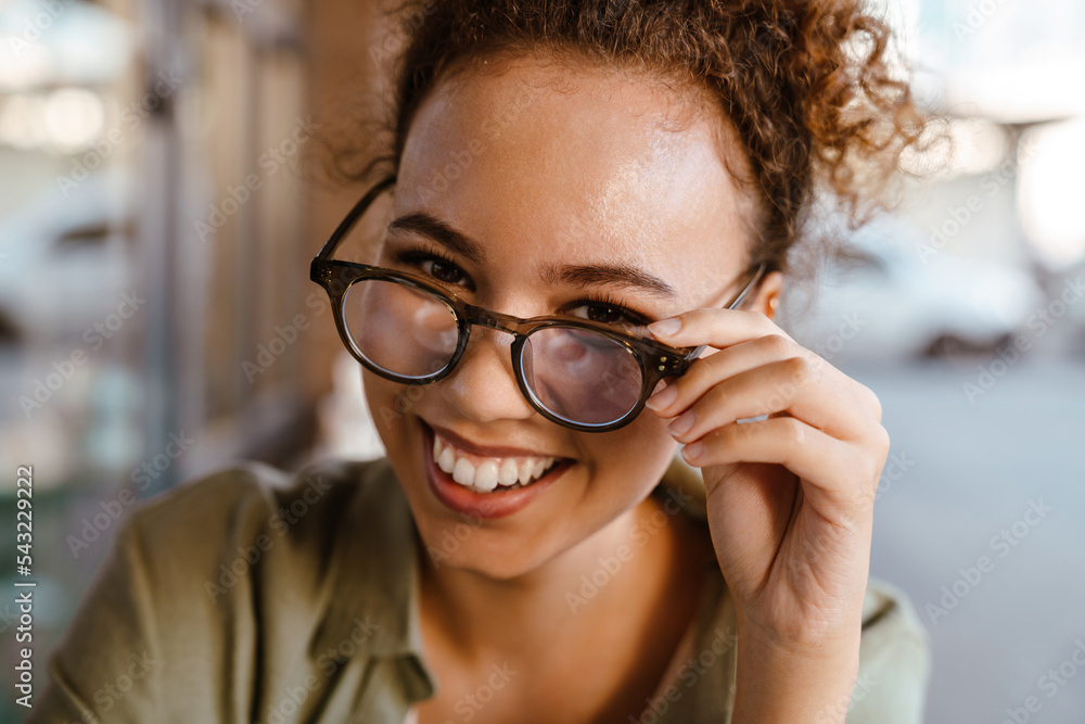 Hispanic woman in eyeglasses smiling while sitting at cafe Hispanic woman in eyeglasses smiling while sitting at cafe