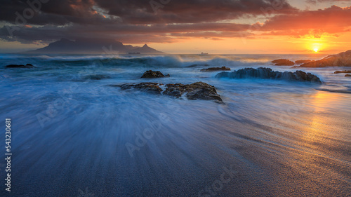 Slow-motion waves during a stormy December Sunset of Table Mountain taken from Bloubergstrand