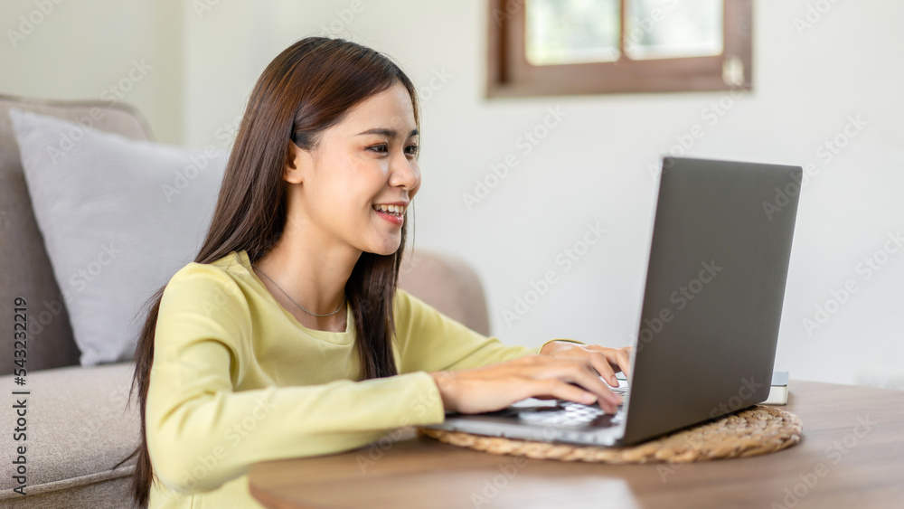 Young woman is sitting to smiling on the floor and using laptop to typing business report while working Young woman is sitting to smiling on the floor and using laptop to typing business report while working