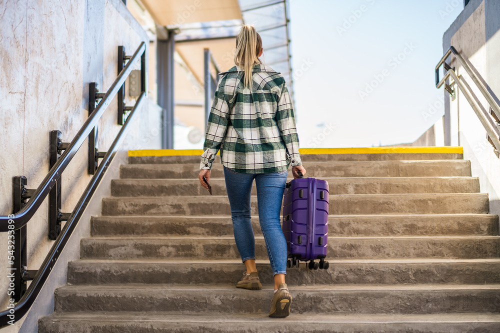 Woman with suitcase and ticket going up by stairs in the train station. Woman with suitcase and ticket going up by stairs in the train station.