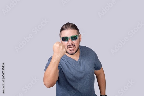 A hostile and irate man threatens to hit someone with his fist. Isolated on a gray background.
