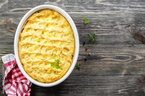 Potato mushroom bake in baking dish on wooden background. Top view, copy space, flat lay. photo