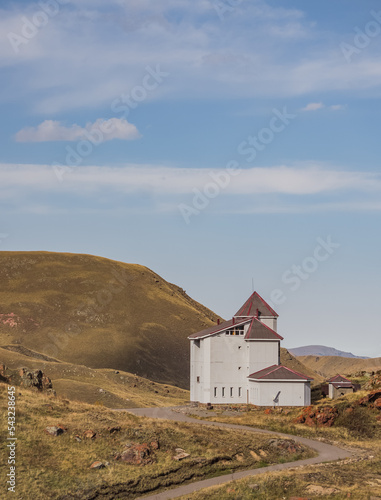 A lonely building and a road to it in the mountains in autumn, on the edge of a cliff, on an autumn day in the Caucasus