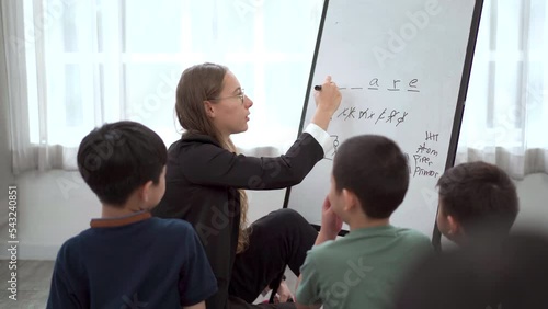 Teacher playing a hangman and crosswords with little children. photo