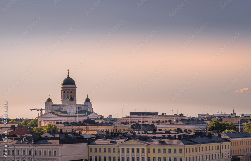 Helsinki, Finland - July 19, 2022: Sunset over city landscape with cathedral in half lighted sky. Lookiing north fron the sea