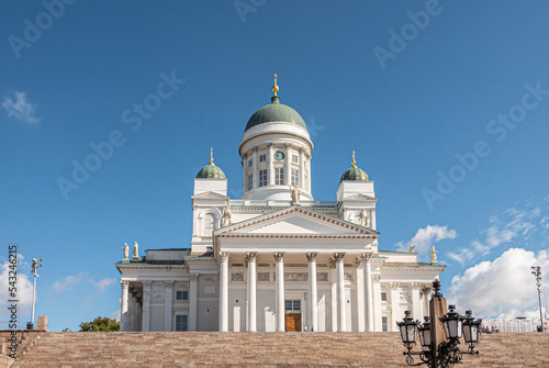 Helsinki, Finland - July 19, 2022: Lantern in front of the white Cathedral against blue sky with, featuring dome and statues. Wide brown stone staircase up front
