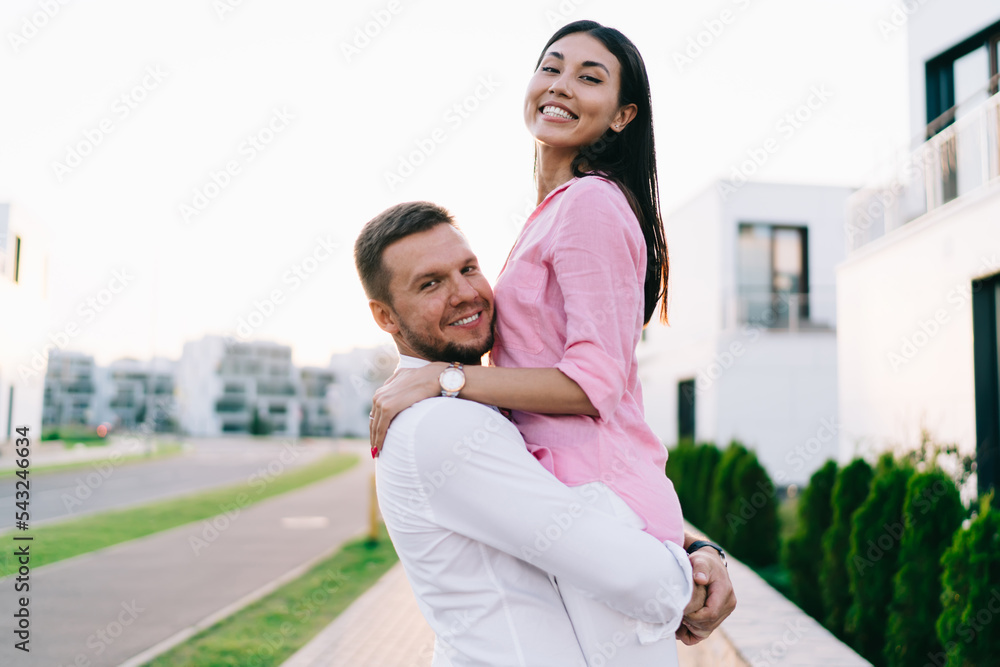 Happy diverse romantic couple embracing on sidewalk and looking at camera Happy diverse romantic couple embracing on sidewalk and looking at camera
