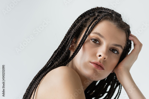 Portrait of young woman with braids looking at camera isolated on grey.