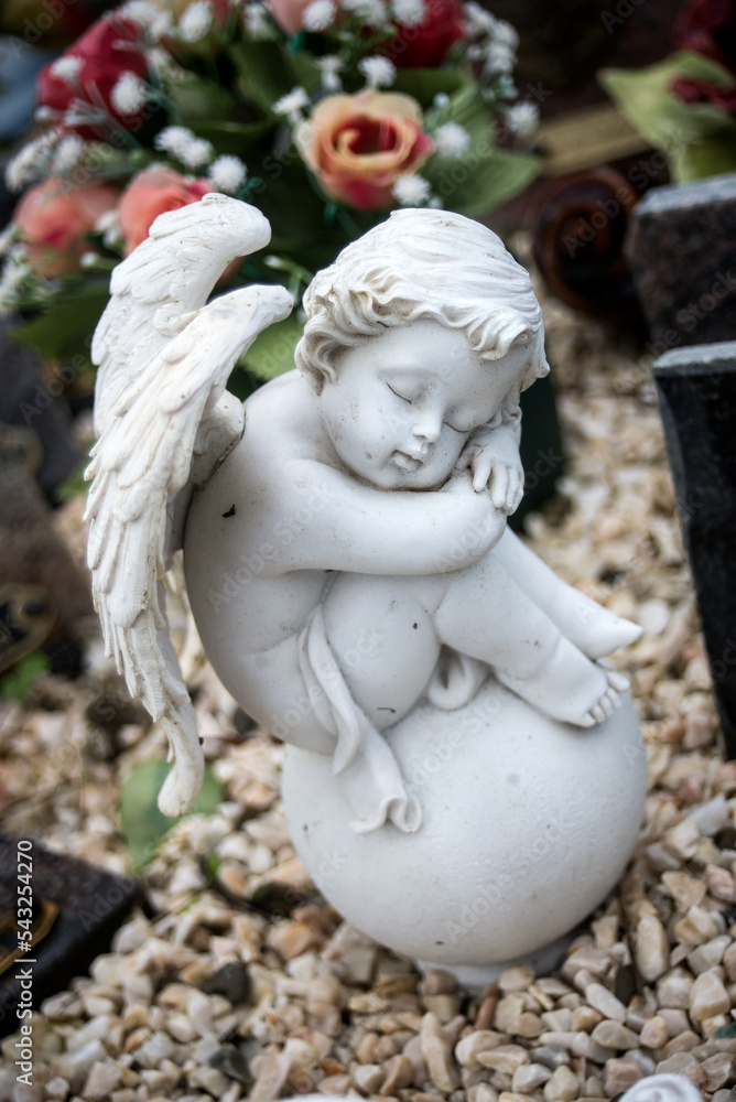 closeup of stoned angel sitting on tomb at the cemetery closeup of stoned angel sitting on tomb at the cemetery