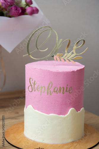 cake with a candle and a topper "one", a cake for 1 year old for a girl