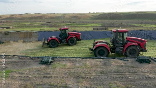 Two Red Tractors Tamp Silage in the Silo Trench