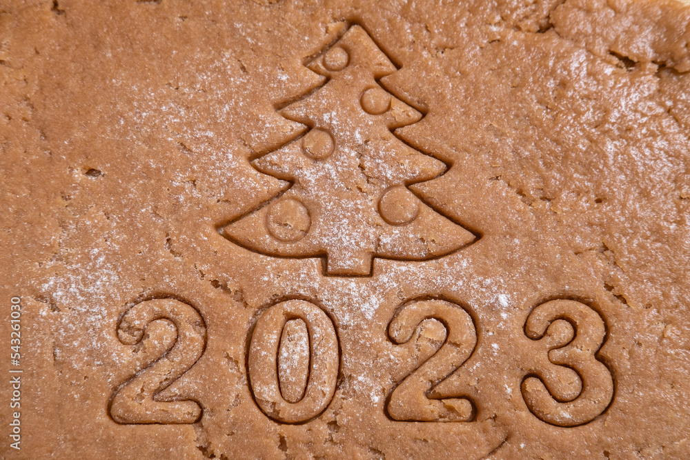 The figures of the year 2023 and the Christmas tree are cut out of gingerbread dough. We cook homemade gingerbread at home. New Year's card from the test.