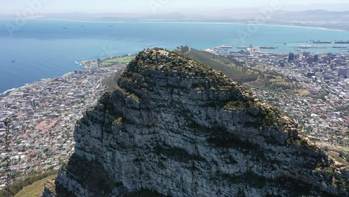 aerial video view - flying around the peak of Lion's Head mountain in Cape Town, South Africa, with a view of Downtown Cape Town,  Seaport, Camps Bay and Robben Island - K4 movie 