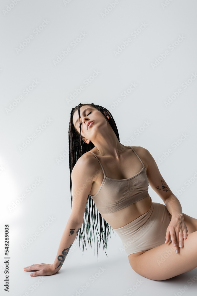 Fit woman in panties and sports bra sitting on grey background. Fit woman in panties and sports bra sitting on grey background.