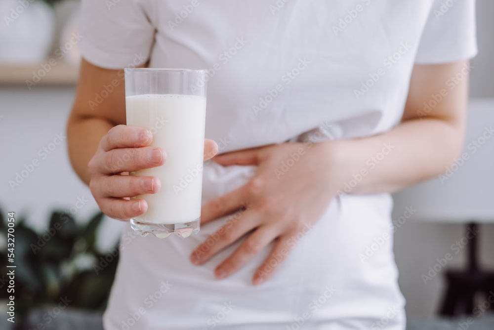 Close up of unrecognizable unhealthy young woman holding glass of milk