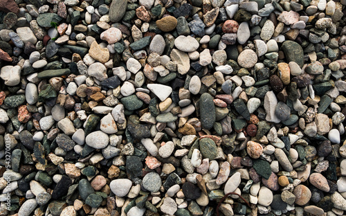 Pattern and texture of small pebbles of different colors in the mountains, texture for a background with soft lighting