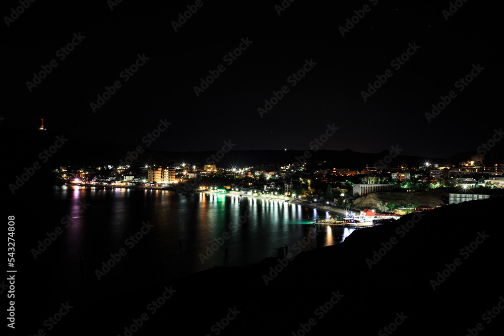 Night city with lights on the background of mountains.