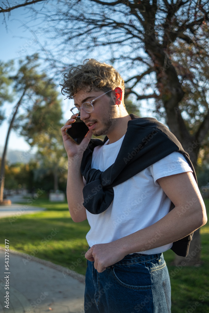 portrait of modern young business person talking on phone and smiling in park in city portrait of modern young business person talking on phone and smiling in park in city