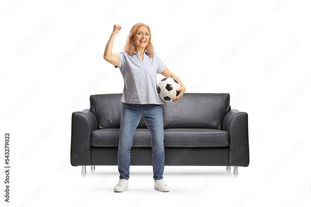 Mature woman holding a football and cheering in front of black sofa Mature woman holding a football and cheering in front of black sofa