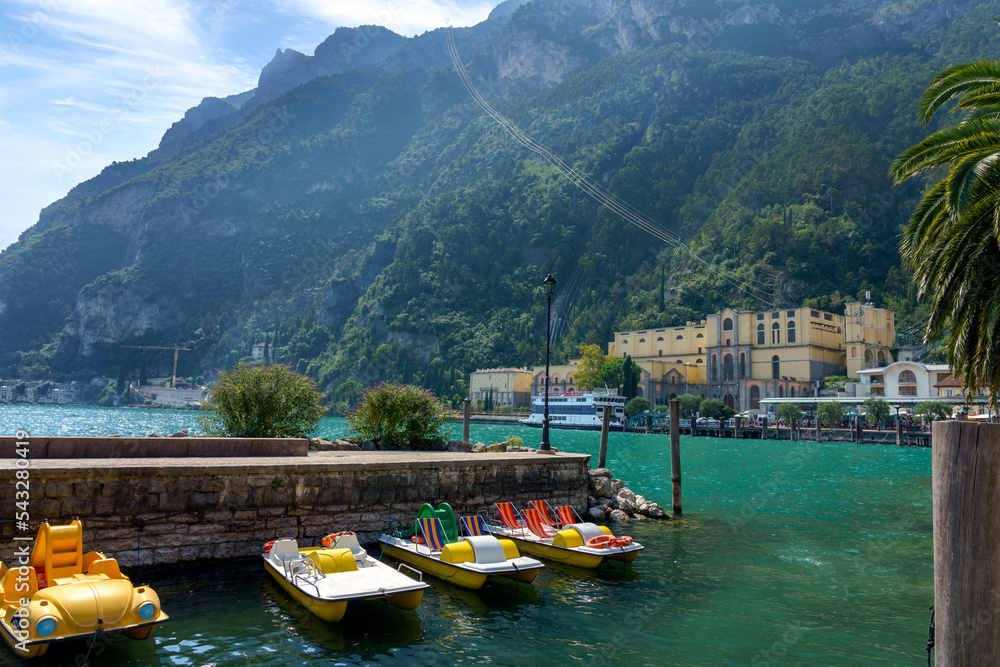 View of Riva del Garda at the foot of the mountains. Boat station in the foreground. Cable road to the hills. Garda lake, Italy.