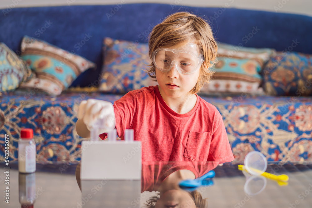 Kid boy doing chemical experiment at home. Child with protective
