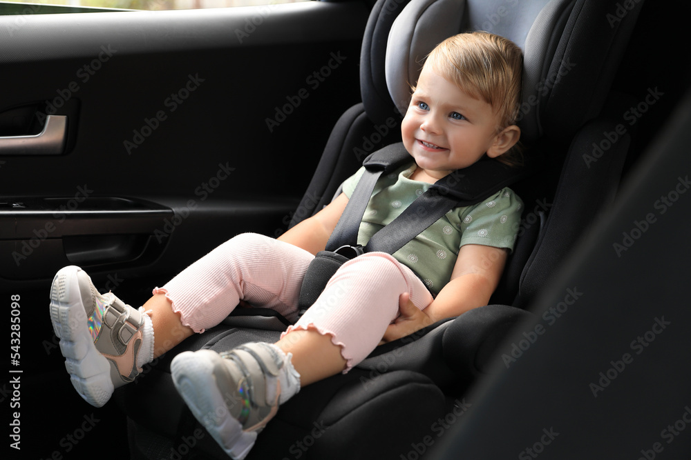 Cute little girl sitting in child safety seat inside car Cute little girl sitting in child safety seat inside car