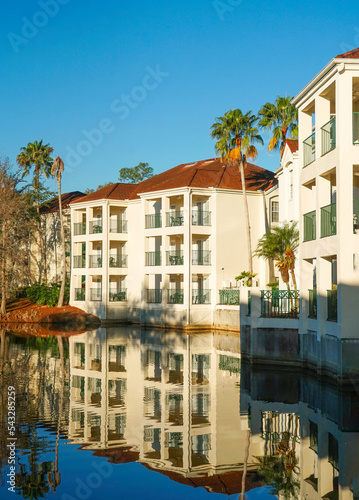apartment buildings with palm tree in tropical area reflection in pond