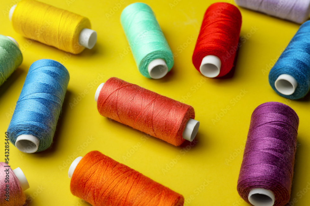 Different colorful sewing threads on yellow background Different colorful sewing threads on yellow background