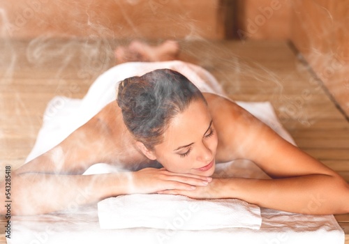 Happy woman relaxing in hot sauna with steam.