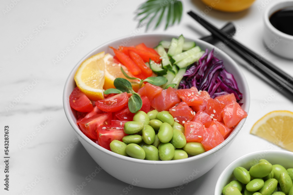 Poke bowl with salmon, edamame beans and vegetables on white marble table Poke bowl with salmon, edamame beans and vegetables on white marble table