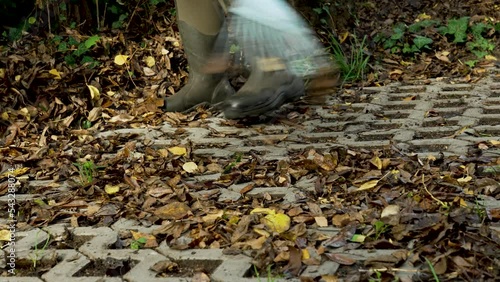 Close up of raking up fallen autumn leaves in the driveway of a property.