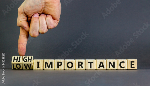 High or low importance symbol. Concept words High importance and Low importance on wooden cubes. Businessman hand. Beautiful grey background. Business high or low importance concept. Copy space.