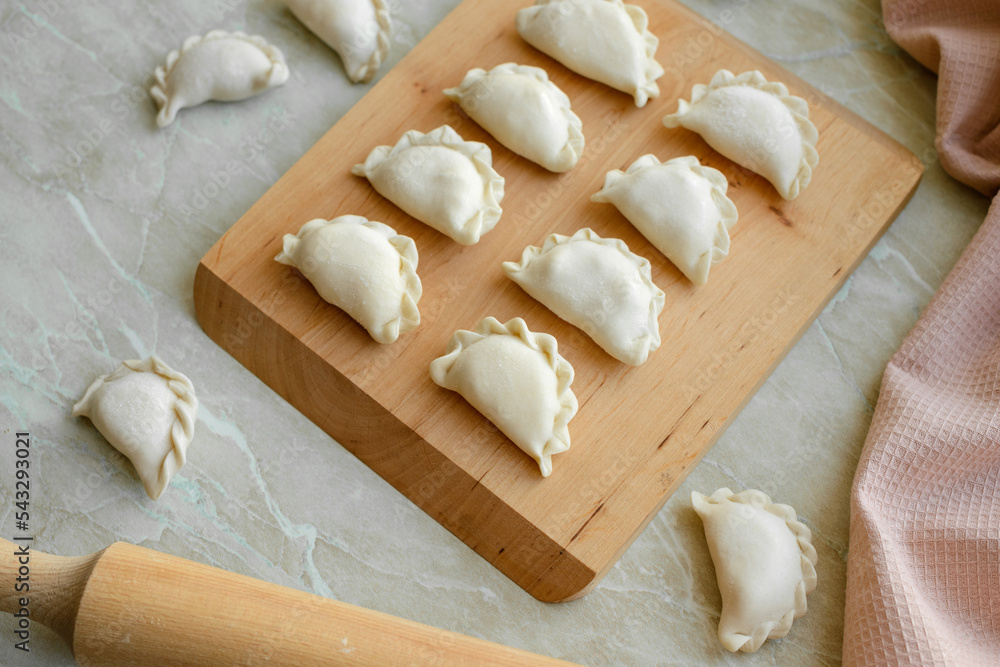 Beautiful raw stuffed dumplings on a wooden cutting board Beautiful raw stuffed dumplings on a wooden cutting board