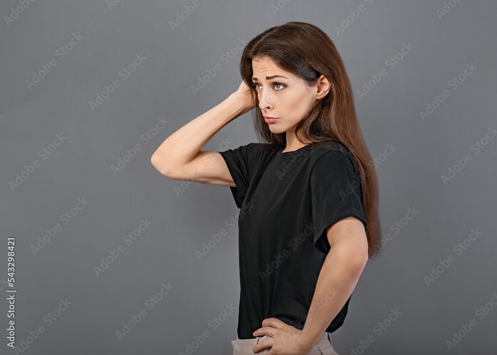 Puzzled doubt thinking young brunette woman looking serious up on empty copy space grey studio background in black casual t-shirt. Puzzled doubt thinking young brunette woman looking serious up on empty copy space grey studio background in black casual t-shirt.