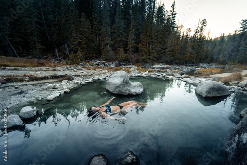 Woman floats in and enjoys the thermal healing waters geothermal hot springs in nature in the back country of Idaho USA.