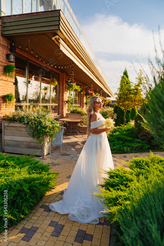 beautiful blonde bride with a bouquet of callas on the path in the garden.