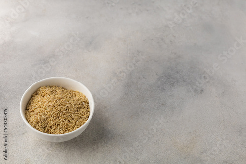Bowl of dry long grain white rice on a light background