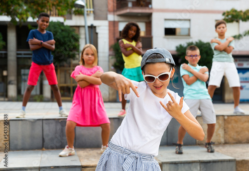 Young boys and girls dancing outdoors. They're performing street dance moves and having fun.