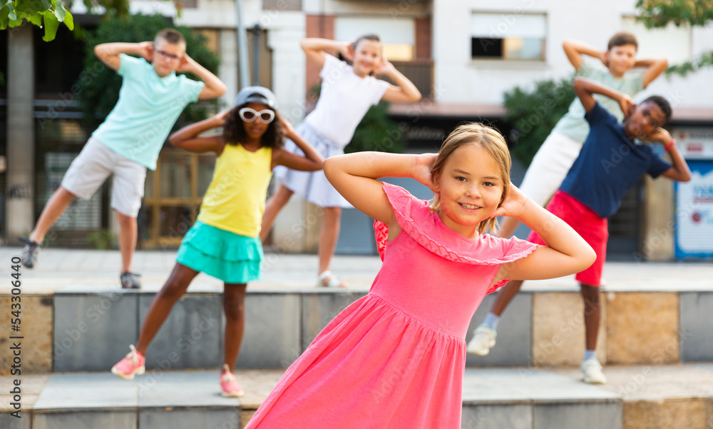 Group of multiracial positive kids performing street dance outdoors.