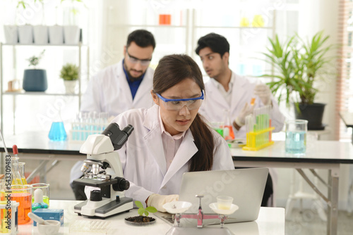 A group of research medical scientists, male and female, working with microscope testing equipment in the laboratory. A professional scientist analyzing biochemical samples on a microscope in a lab.