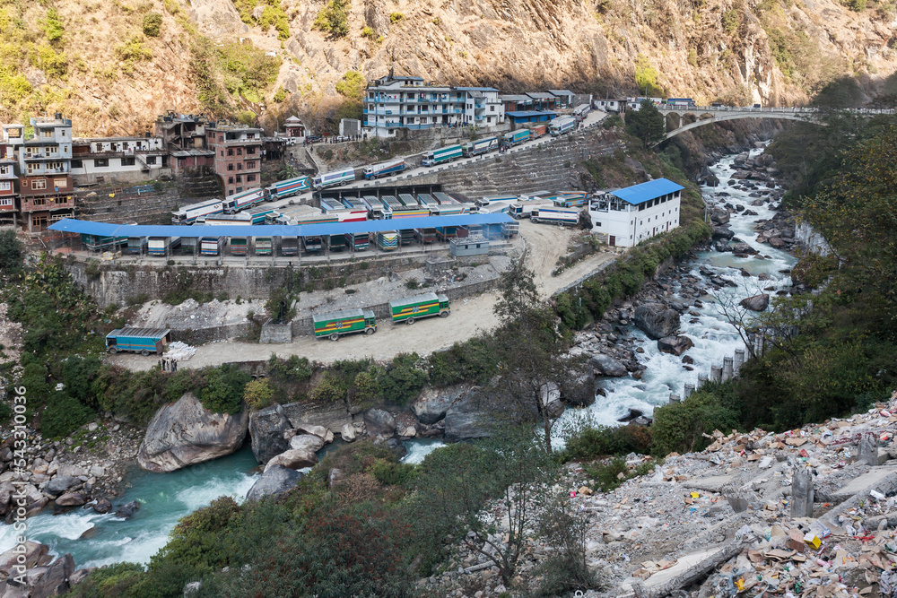 KODARI, NEPAL: border town, and Sino-Nepal Friendship Bridge, over Sun Kosi river. Trucks waiting for custom inspection. The bridge marks the end of China National Highway 318 (G318) - obrazy, fototapety, plakaty 