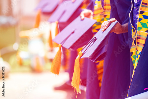 selective focus of hat in a row- filtered image of african people in a graduation costume