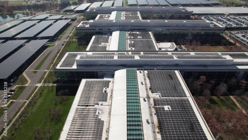 Wide establishing shot of layers and rows of solar panels absorbing the sun's energy for power and electricity on the exterior and roof of a large building site Wide establishing shot of layers and rows of solar panels absorbing the sun's energy for power and electricity on the exterior and roof of a large building site